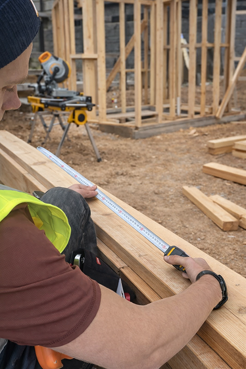 Construction worker measuring timber